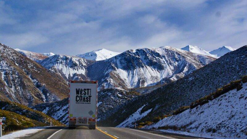 LKW auf dem Highway vor verschneiten Bergen