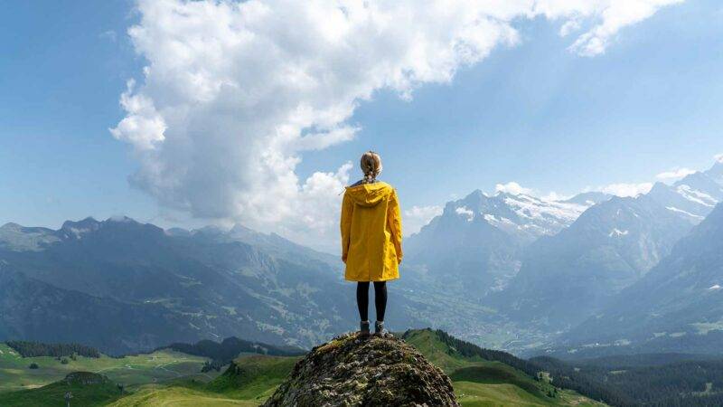 Person mit Regenjacke vor Bergen im Hintergrund